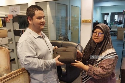 Mike returning the E-Braille laptop to Puan Nor Afifah Shabani from E-BRELLE after the team reviewed the tool
